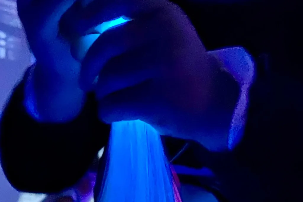 Mani che esplorano fibre ottiche luminose durante un’attività sensoriale